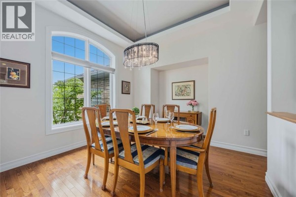 Formal dining room with a large arched window, hardwood floors, and a wooden dining set. - 4303 Garden Crescent, Petrolia