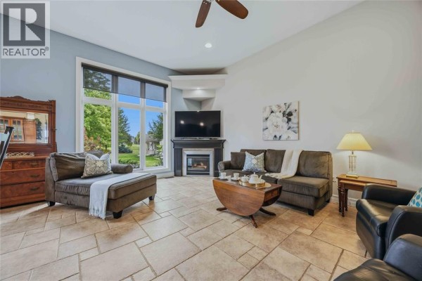Living room with large windows, a fireplace, sofa, and tiled floor. - 4303 Garden Crescent, Petrolia