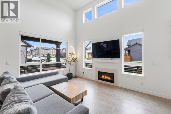 Spacious living room with high ceilings, large windows, a fireplace, and a sectional sofa. - 4306a Cormorant Way, Tsawwassen
