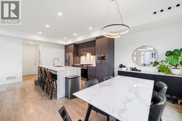 Open concept dining and kitchen area with a marble-top dining table and island seating. - 4306a Cormorant Way, Tsawwassen
