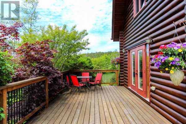 Deck with red chairs and table overlooking lush greenery and trees. - 431-435 Dogberry Hill Road, Portugal Cove St  Philips