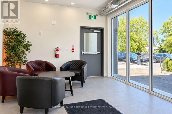 Small waiting area with maroon and black leather chairs, a round table, and large windows. - 431 Davis Drive, Newmarket