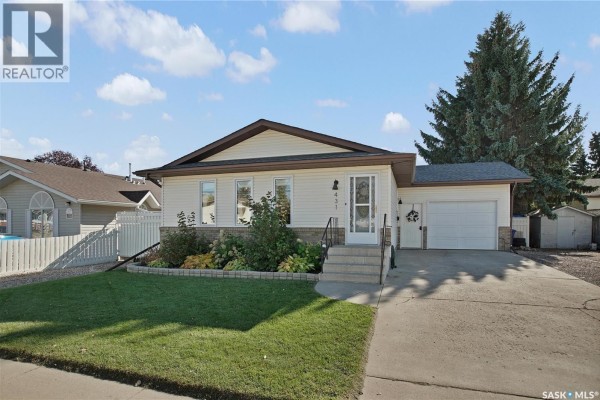 Front exterior of a white and brick bungalow with a green lawn and mature trees. - 431 Peters Street, Warman