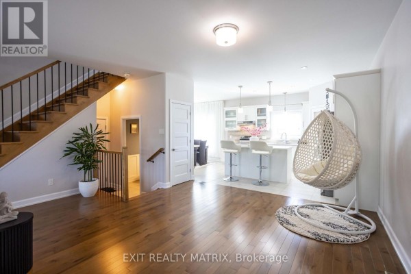 Open concept living area with hardwood floors, a staircase, and a white kitchen with island. - 431 Provence Avenue, Russell