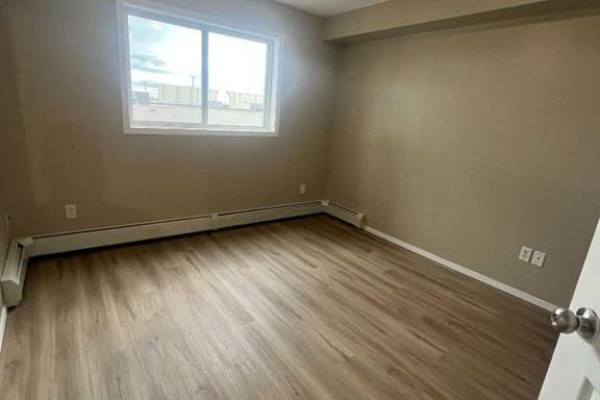 Kitchen with light wood cabinets, beige countertops, a double sink, and a black stove. - 4312, 4975 130 Avenue Se, Calgary