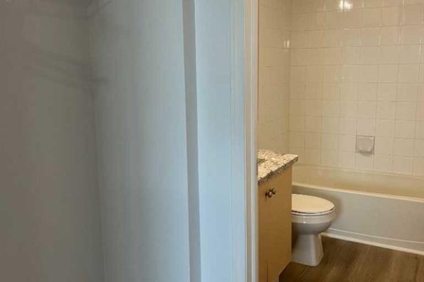 Bathroom with white tiled walls, a white bathtub, and a vanity with speckled countertop. - 4312, 4975 130 Avenue Se, Calgary