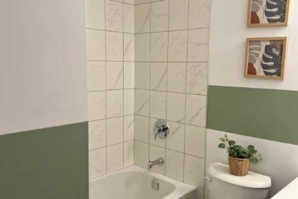 Full bathroom with a white bathtub, marble tile shower surround, and a green and white striped accent wall. - 432 - 10 Mallard Trail, Hamilton