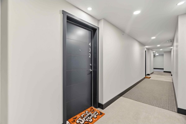 Hallway leading to apartment 432 with a dark gray door and beige carpet. - 432 5415 Brydon Crescent, Langley
