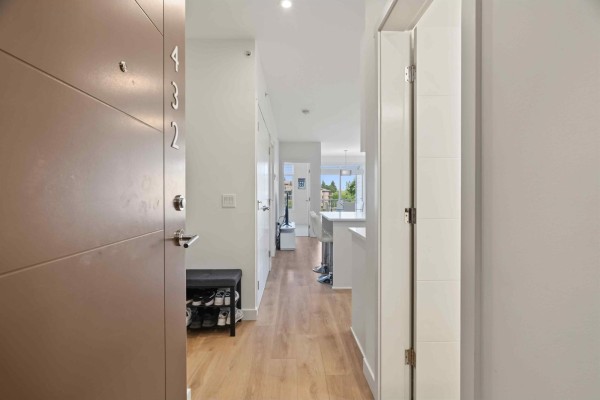 View from inside apartment entrance showing a narrow hallway and open living area. - 432 5415 Brydon Crescent, Langley