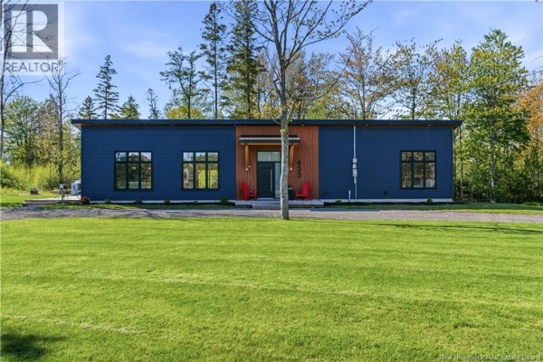 Exterior deck with outdoor furniture and a covered seating area attached to a dark blue sided structure. - 433 Cornwall Road, Shediac