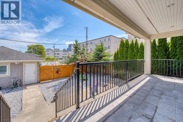 View from a covered patio looking towards a backyard with a detached garage and fence. - 4330 William Street, Burnaby