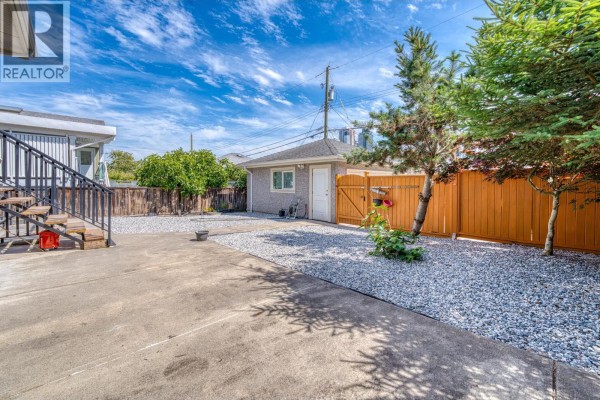 Backyard with concrete patio, gravel landscaping, detached garage, and wooden fence. - 4330 William Street, Burnaby