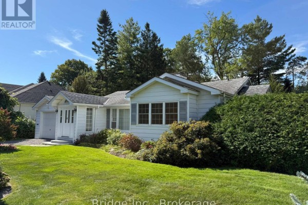 Side view of a white bungalow with a green lawn and dense shrubbery on a sunny day. - 434 Apple Lane, Mississauga