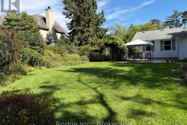 Spacious green backyard with landscaping, a white gazebo, and large trees. - 434 Apple Lane, Mississauga