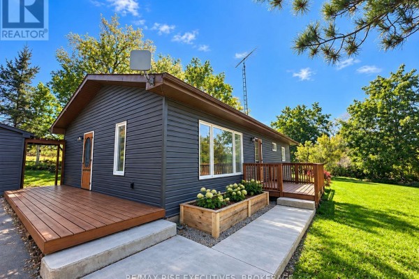 Large grassy yard with mature trees, a wooden utility pole, and a distant shed. - 434 County Rd 9, Greater Napanee