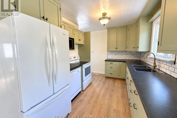 Living room with hardwood floors, large bay window, yellow walls, and white ceiling. - 434 County Rd 9, Greater Napanee