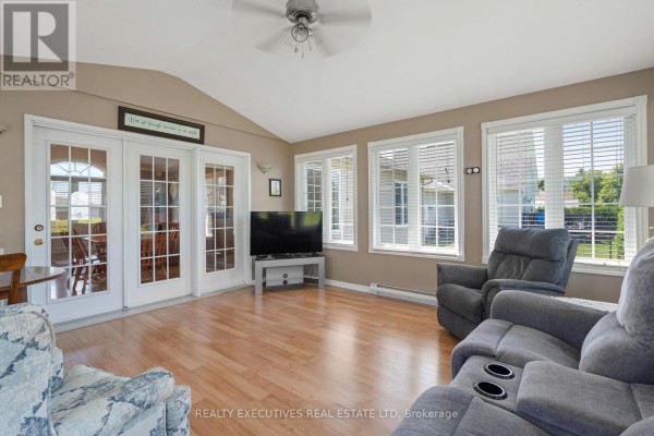 Sunroom with french doors, a television on a stand, and recliners near large windows. - 434 Queen Street, North Dundas