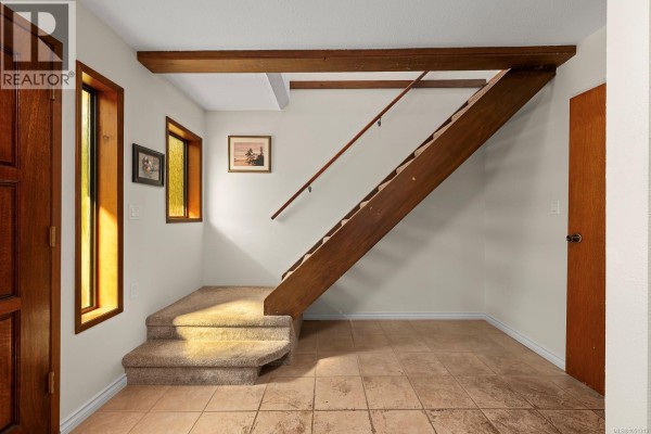 Interior entryway with tiled floor, carpeted stairs, and wooden banister. - 4344 Briardale Rd, Royston