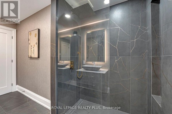 Ensuite bathroom with a walk-in shower, double vanities, vessel sinks, and grey tiled walls. - 4344 Dallas Court, Mississauga