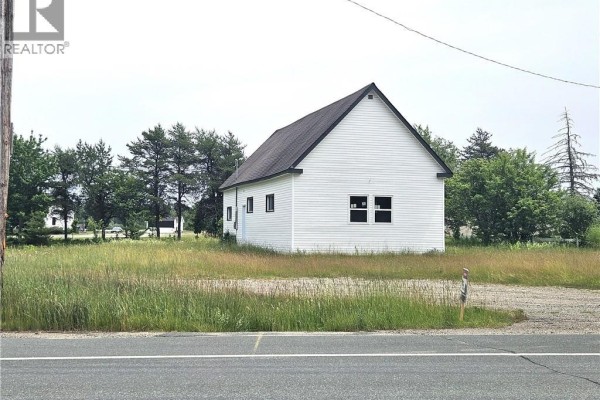 Side view of a white commercial building with a dark roof, next to trees and grass. - 4344 Route 11, Covedell