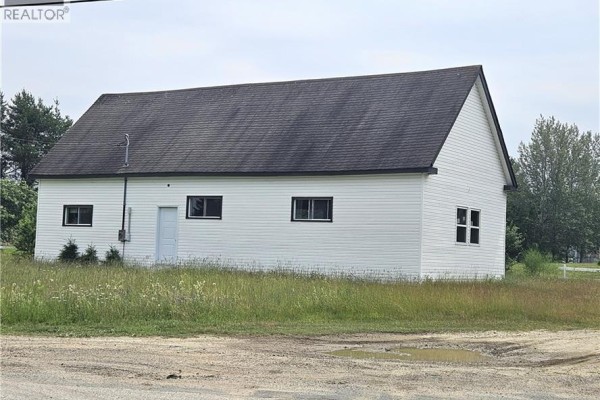 Rear view of a white commercial building with a dark roof and two windows. - 4344 Route 11, Covedell