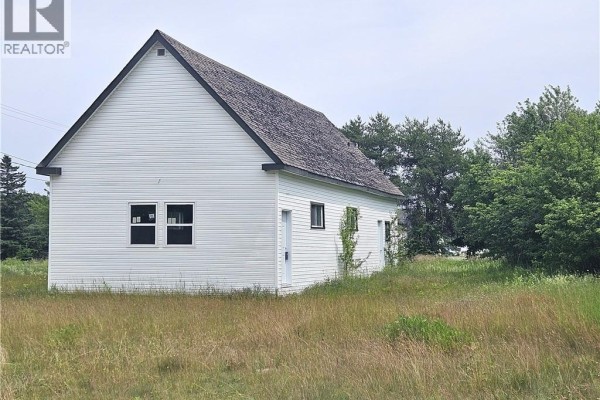 White commercial building with a dark roof, seen from across a grassy field with trees. - 4344 Route 11, Covedell