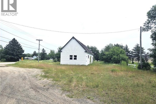 Aerial view of a white commercial building with a dark roof, surrounded by green fields and trees. - 4344 Route 11, Covedell