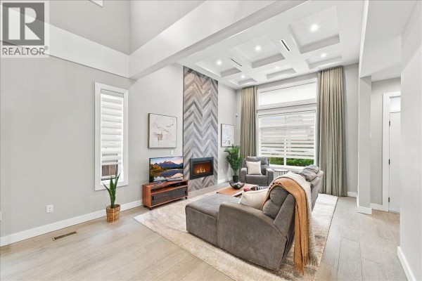 Living room with a grey sectional sofa, fireplace, and coffered ceiling. - 4348 Carleton Avenue, Burnaby