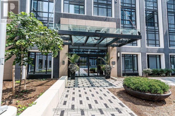 Building entrance with a glass awning, planters, and patterned walkway. - 435 - 5 Mabelle Avenue, Toronto
