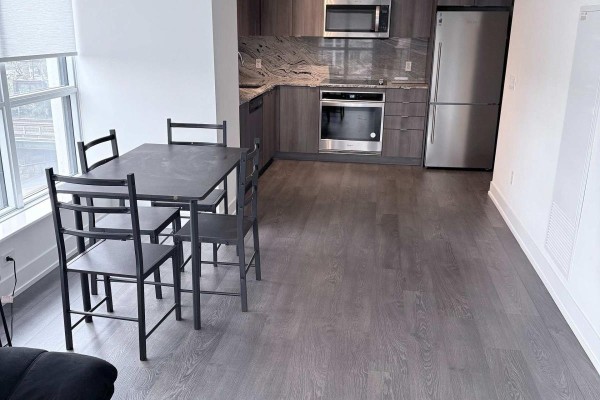 Modern kitchen with stainless steel appliances, dark wood cabinets, and dining table. - 435 - 5 Mabelle Avenue, Toronto