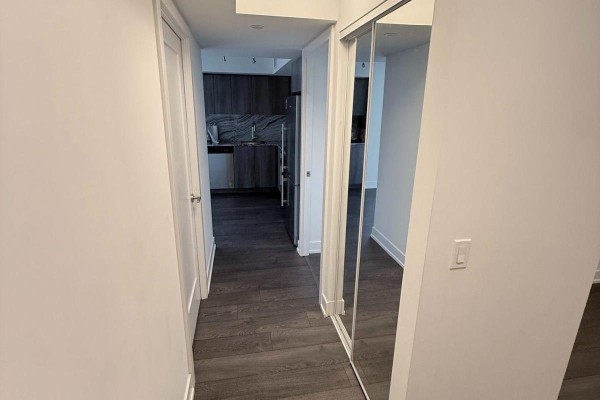 Hallway with mirrored closet doors leading to the kitchen area. - 435 - 5 Mabelle Avenue, Toronto