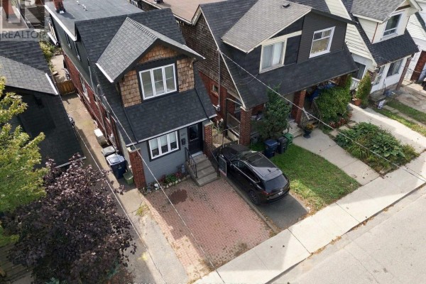 Close-up of the front door entrance with grey siding and brick pillars. - 435 Mortimer Avenue, Toronto