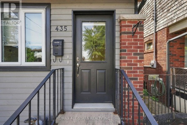 Interior view of a small entryway with a black door and a wooden coat rack. - 435 Mortimer Avenue, Toronto