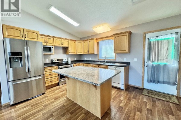 Kitchen with light oak cabinets, stainless steel appliances, and granite-topped island. - 435 Southwood Drive, Prince Albert