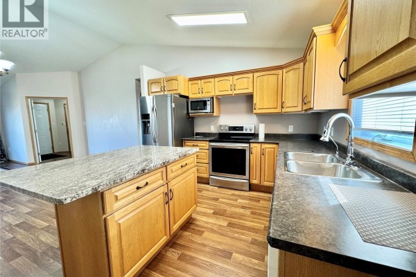 Kitchen view showing wood cabinets, stainless steel sink, dishwasher, and granite countertops. - 435 Southwood Drive, Prince Albert
