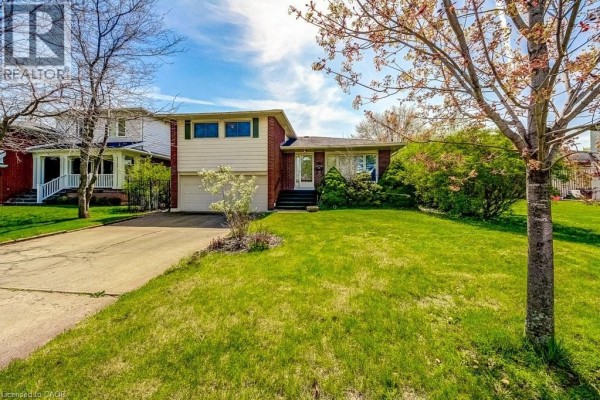 Front exterior of a residential house with green lawn and blooming trees. - 4356 Dublin Crescent, Burlington