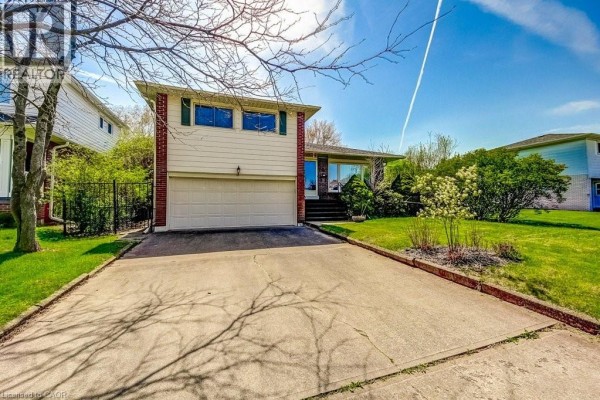 Front view of a two-story house with beige siding, red brick accents, and green shutters. - 4356 Dublin Crescent, Burlington