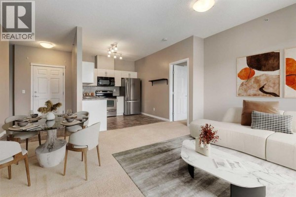 Open concept living and dining area with a kitchen, sofa, dining table, and fireplace. - 436, 1727 54 Street Se, Calgary