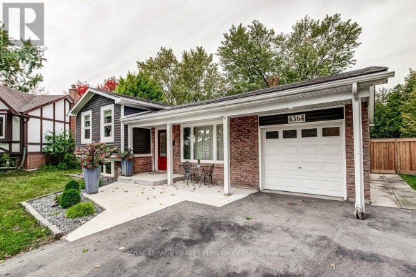 Close-up of the covered front porch with a red door, brick facade, large planters, and a small bistro set. - 4364 Ayr Place, Burlington
