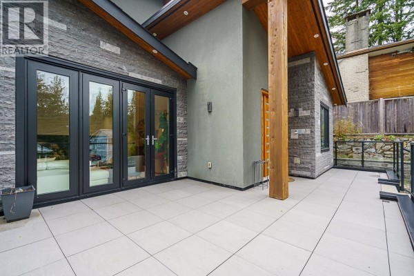Close-up of the modern house entrance with double glass doors and tiled patio. - 4365 Mountain Highway, North Vancouver