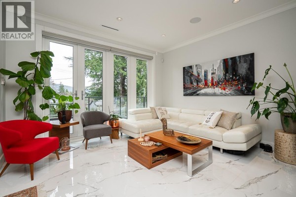 Living room with white sectional sofa, contemporary art, fireplace, and large glass doors. - 4365 Mountain Highway, North Vancouver
