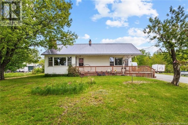 Front view of a white house with a wooden deck and surrounding green lawn. - 4367 Heritage Drive, Tracy