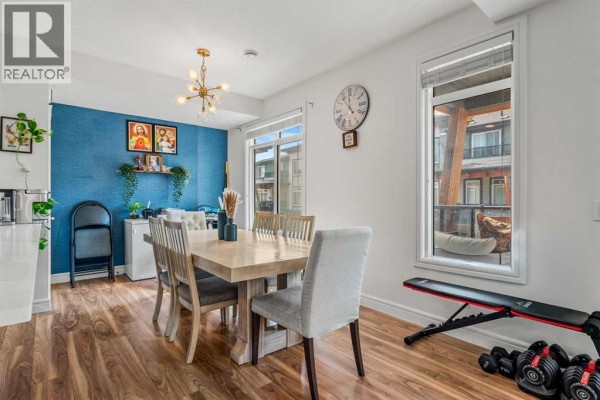 Dining area with a large wooden table, chairs, and a blue accent wall. - 4367 Seton Drive Se, Calgary