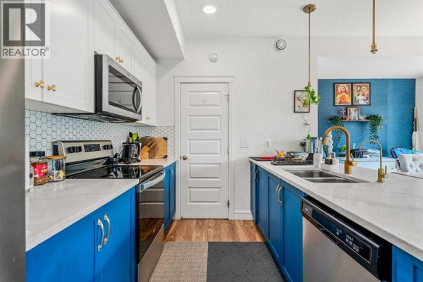 Close-up view of the kitchen counter with a stainless steel sink and blue cabinets. - 4367 Seton Drive Se, Calgary