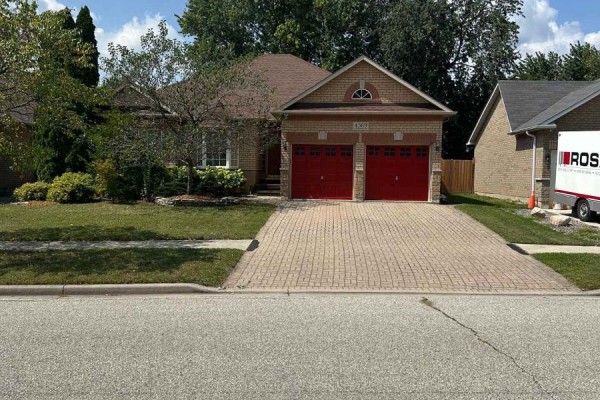 Side exterior view of a brick house with a red double garage door and paved driveway. - 4369 Goldenwood Drive, Windsor