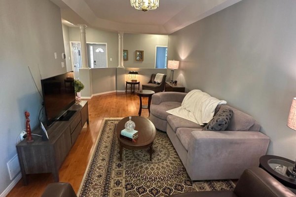 Living room with grey sofa, brown armchair, oval coffee table, and large television. - 4369 Goldenwood Drive, Windsor