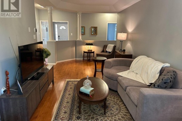 Living room with grey walls, hardwood floors, sofa, armchair, coffee table, and television. - 4369 Goldenwood Drive, Windsor