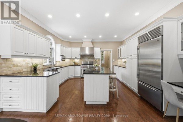 Kitchen with white cabinets, island, stainless steel fridge, and hardwood floors - 437 Cairncroft Road Oakville