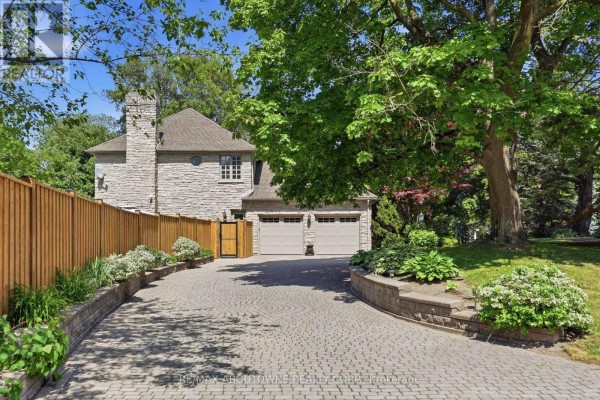 Curved stone driveway leading to a detached three-car garage with beige doors. - 437 Cairncroft Road, Oakville