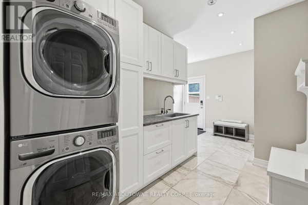 Stacked LG washer and dryer, sink, white cabinets, and tile floor - 437 Cairncroft Road Oakville